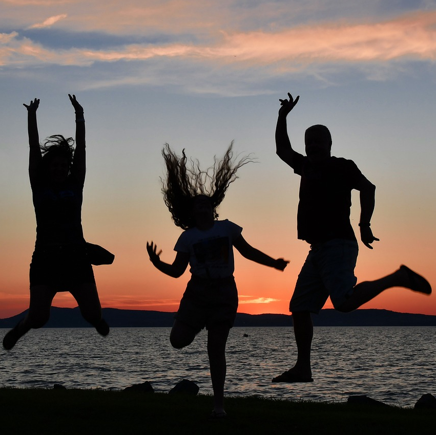 Three people jumping for joy demonstrates holistic wellness.