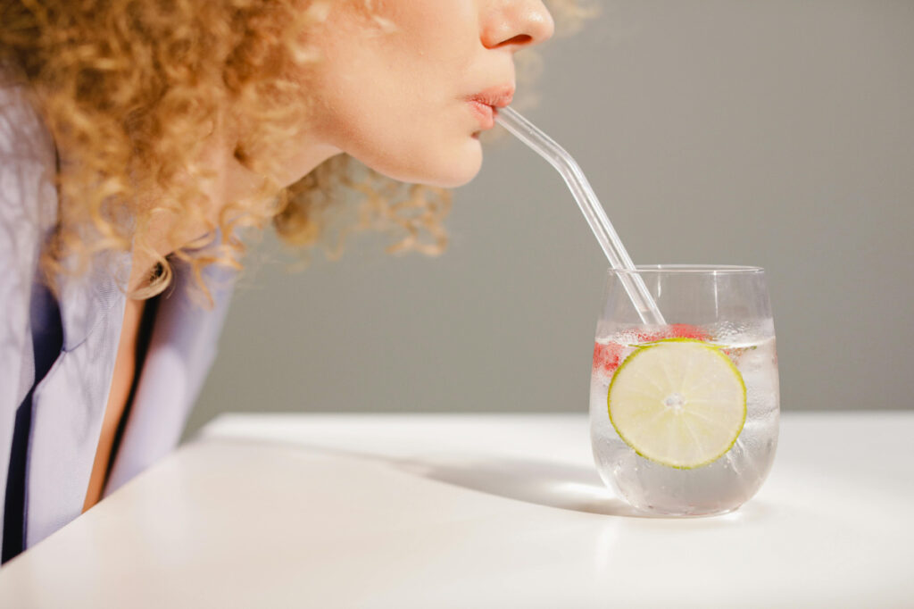 Woman sipping water with lime and berries for hydration.