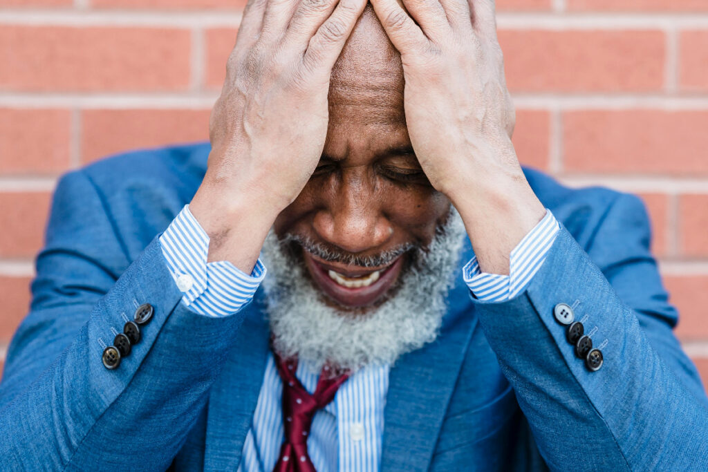 Man depicting how stress affects health - showing his head in hands.