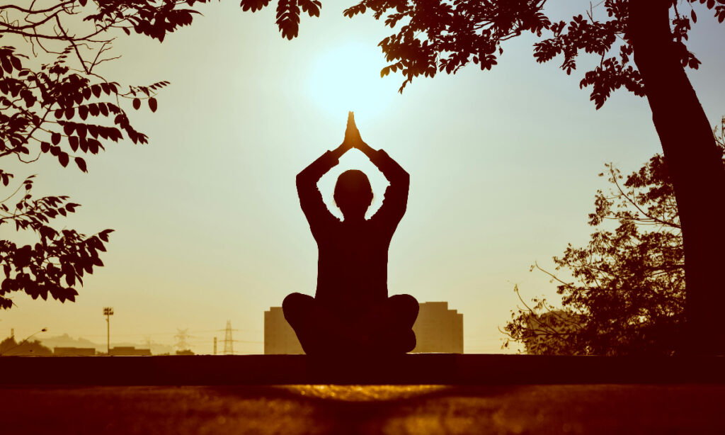 Person practicing yoga at sunrise.